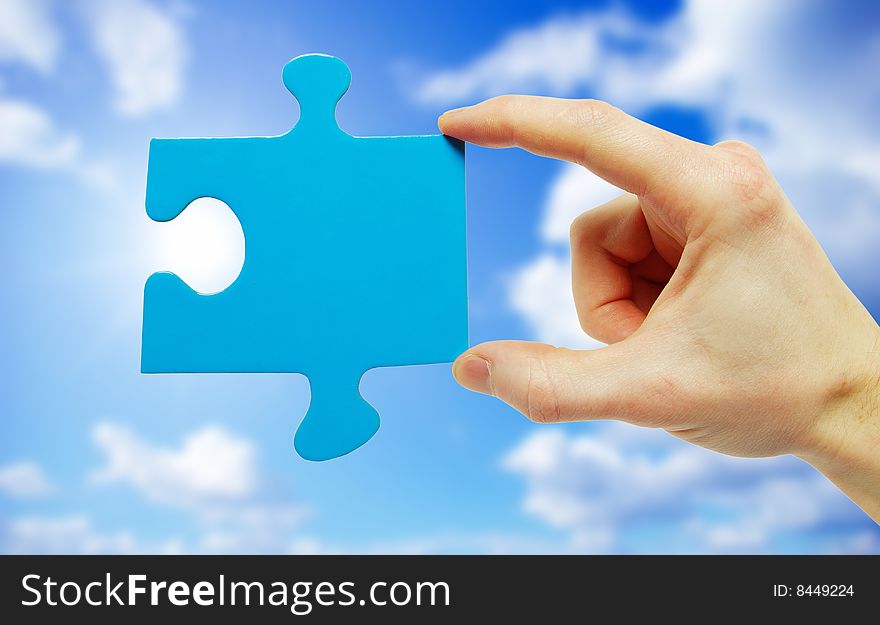 Puzzle in hand isolated on sky background