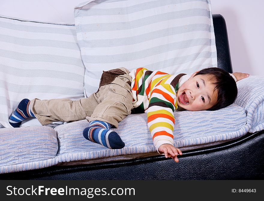 A picture of a little chinese boy playing happily on sofa at home. A picture of a little chinese boy playing happily on sofa at home