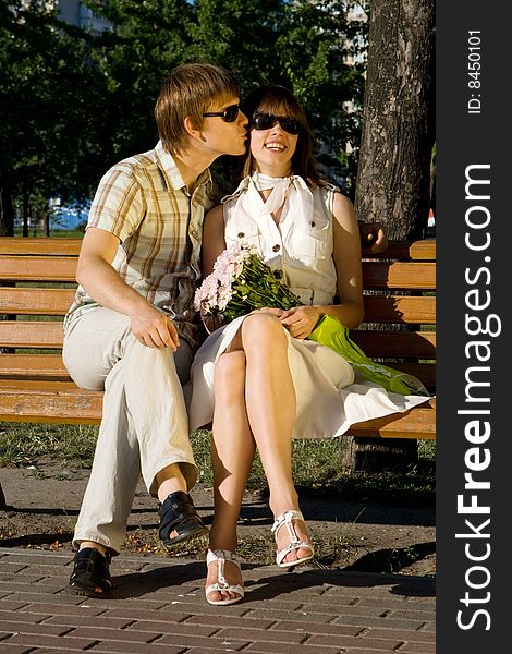 Boy And Girl Kissing On A Bench In A Park