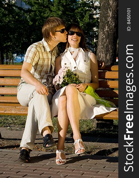 Boy and girl kissing on a bench in a park