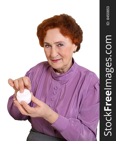 The elderly woman holds in a hand a jar with a cream. The elderly woman holds in a hand a jar with a cream