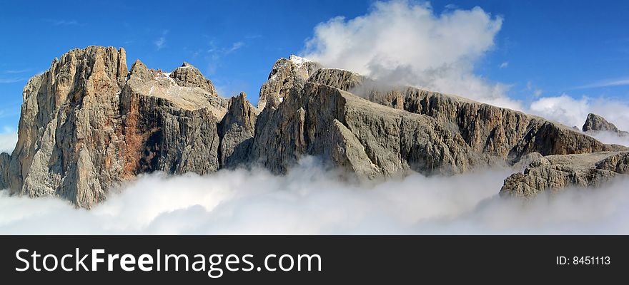 Alpine peaks emerge from the clouds under a blue sky. Alpine peaks emerge from the clouds under a blue sky.