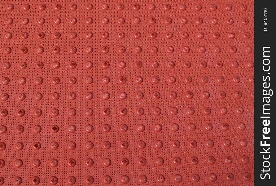 Red bumpy textured non-slip pattern on a sidewalk. Red bumpy textured non-slip pattern on a sidewalk.
