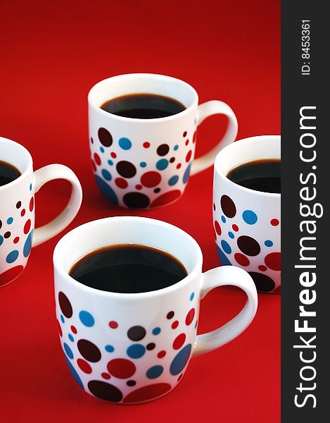 Colorful coffee mugs on red  background