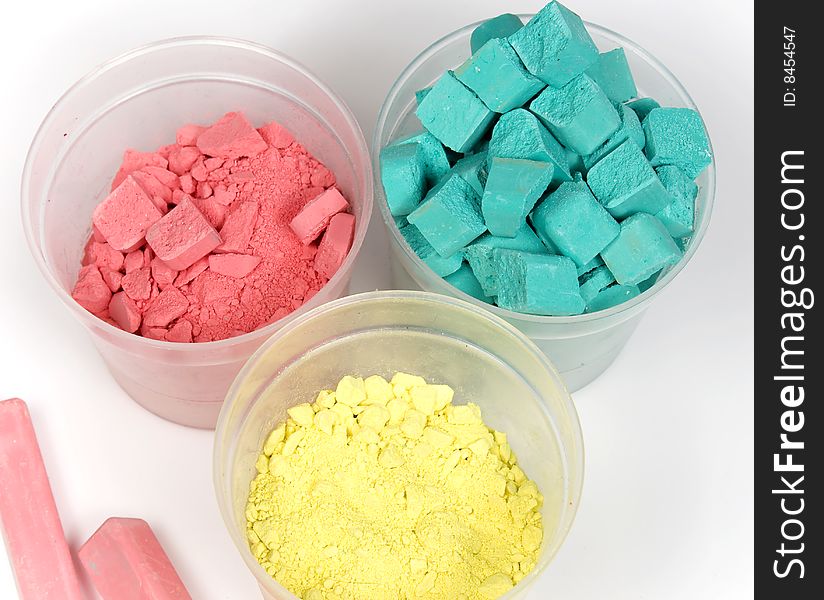 Cyan, magenta and yellow crushed chalk in plastic caps on white