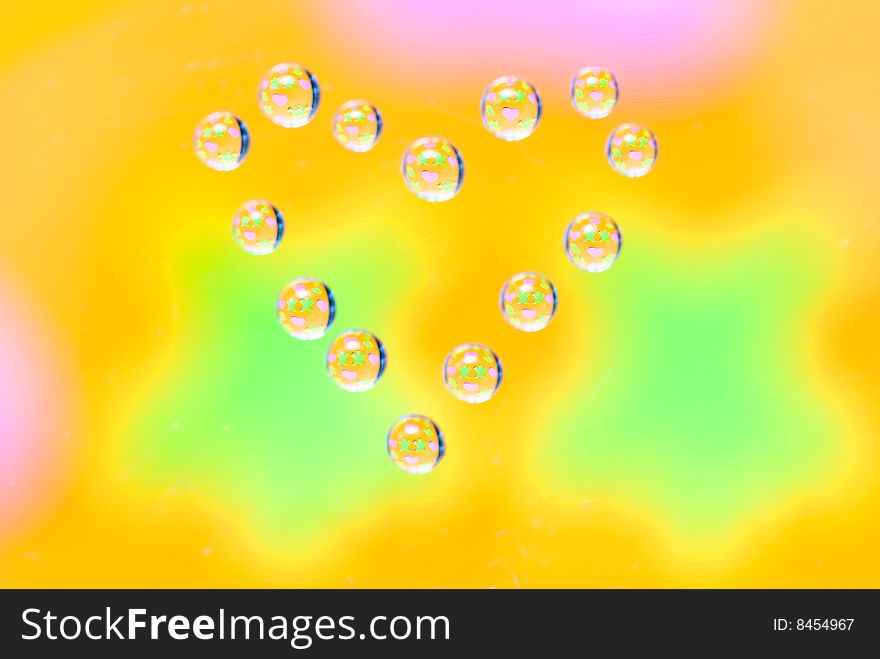 Water drops in the form of heart on a multi-coloured celebratory background