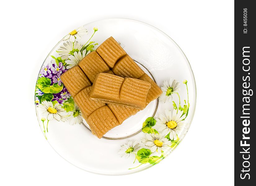 Several toffee in plate on tea saucer decorated flowers