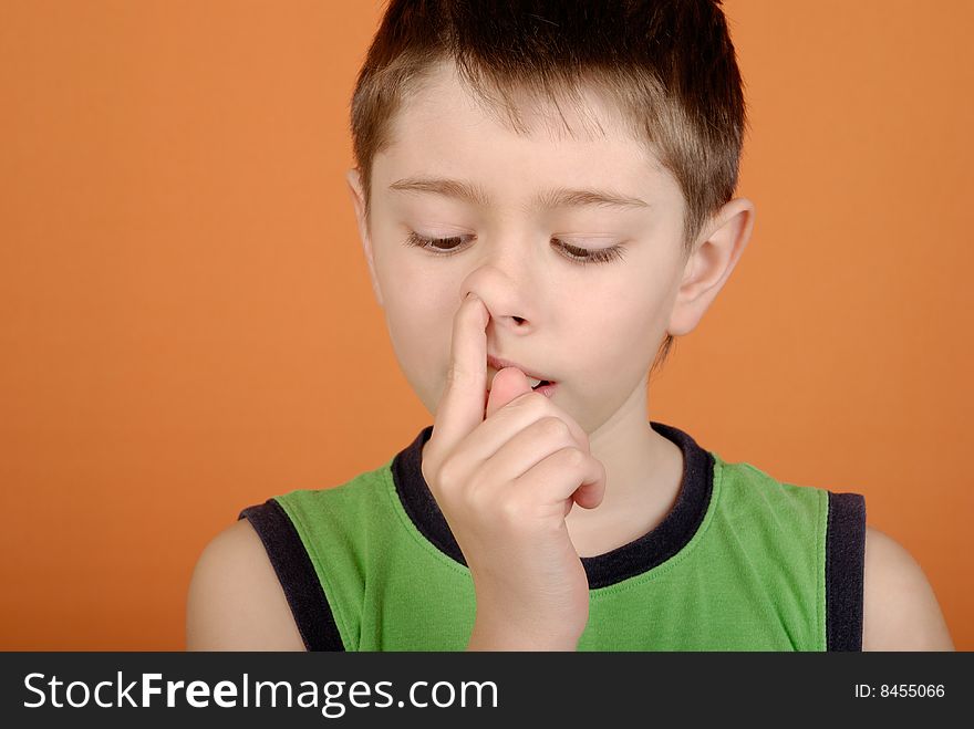 Boy is picked in a nose on an orange background