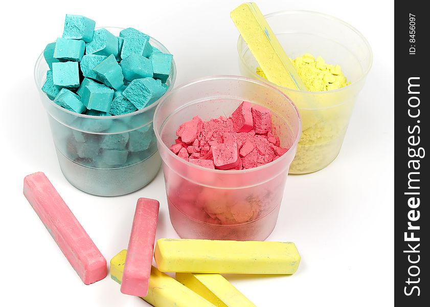 Cyan, magenta and yellow crushed chalk in plastic caps on white