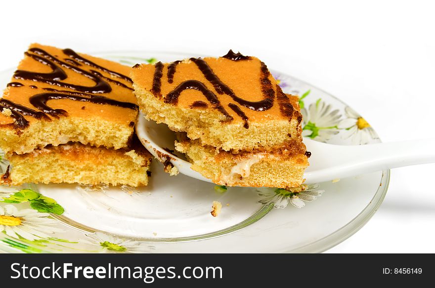 Cake with with ceramical spoon on tea saucer decorated flowers. Cake with with ceramical spoon on tea saucer decorated flowers