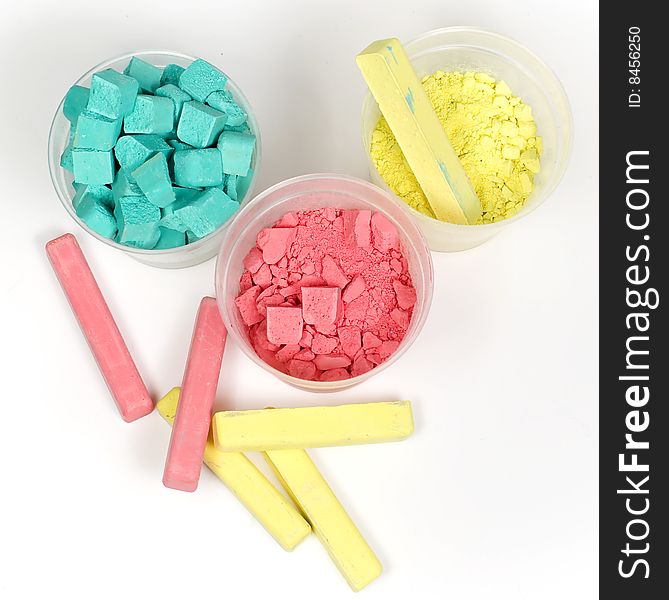 Cyan, magenta and yellow crushed chalk in plastic caps on white