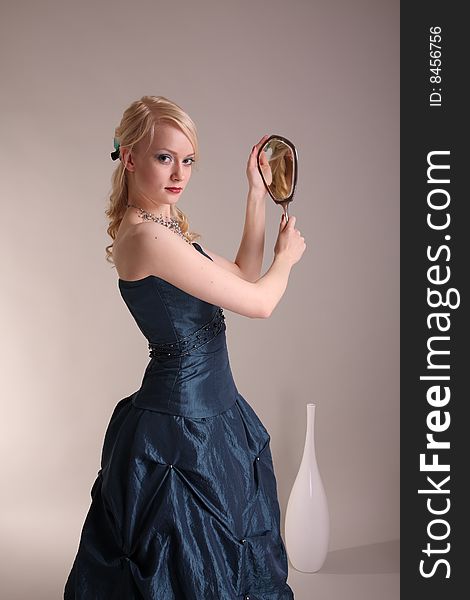 Beautiful young woman wearing a blue prom dress and silver mirror. Beautiful young woman wearing a blue prom dress and silver mirror