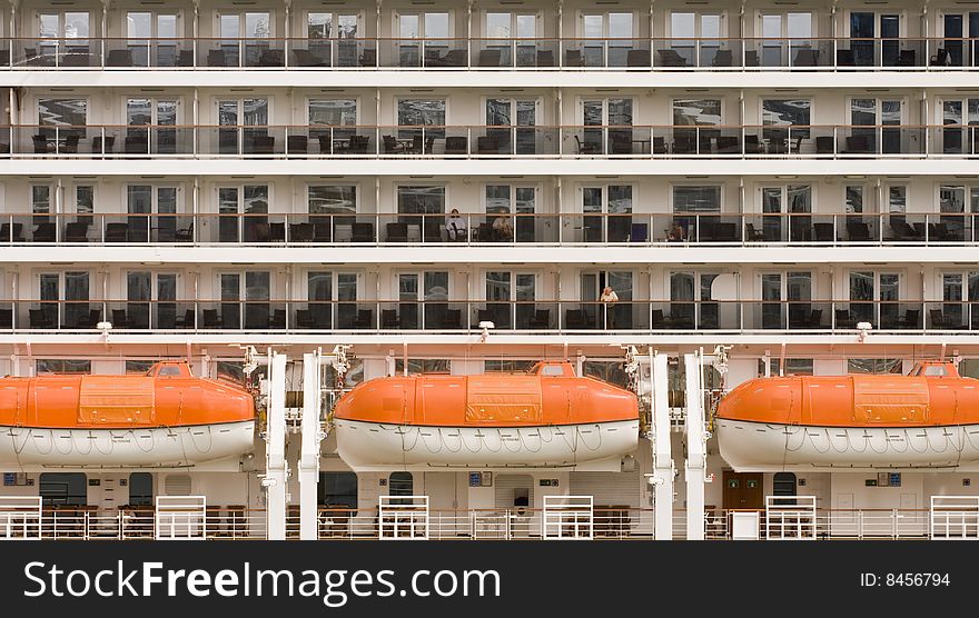 The side of a cruise ship showing balconies and lifeboats