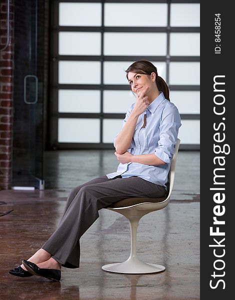 Business woman thinking sitting in a retro chair in a modern office