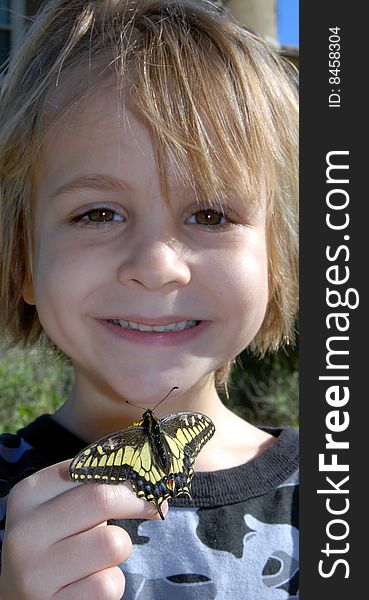 Boy looking at Yellow swallowtail butterfly resting on hand