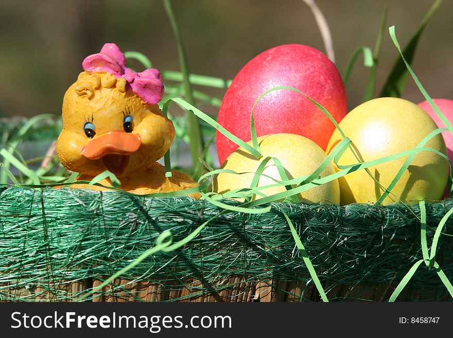 There is a green basket with easter bright yellow and pink eggs. There is a green basket with easter bright yellow and pink eggs.