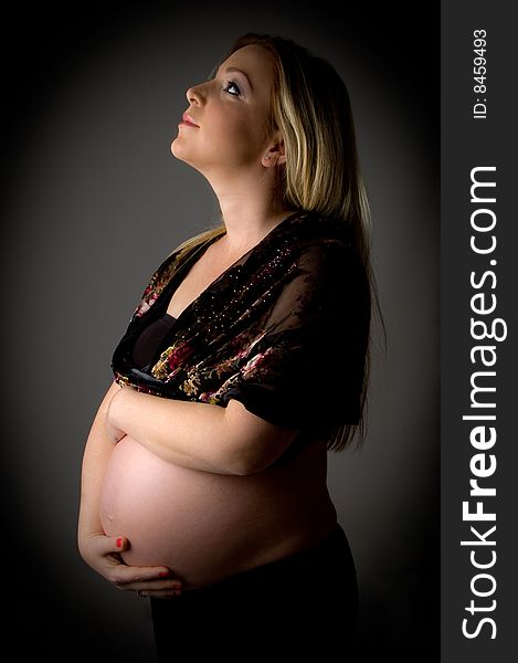 Side view of smiling pregnant female looking up on an isolated background