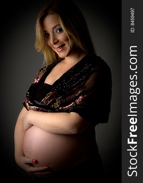 Side view of happy pregnant female looking at camera on an isolated white background