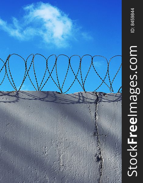 Wall with barbed wire and blue sky