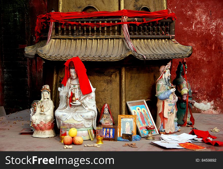 Ceramic Buddha figures, cards, and offerings stand at the base of a small brass pagoda at the Long Xing Temple complex in Pengzhou, China - Lee Snider Photo. Ceramic Buddha figures, cards, and offerings stand at the base of a small brass pagoda at the Long Xing Temple complex in Pengzhou, China - Lee Snider Photo.