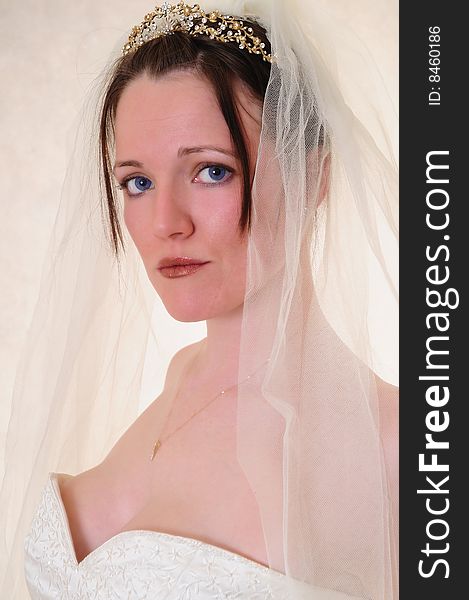 Female model head shot of her in a wedding dress with a comfortable grin on her face. Female model head shot of her in a wedding dress with a comfortable grin on her face.