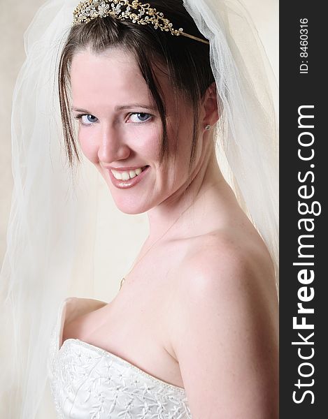 Female model standing in her wedding dress in a studio smiling at the camera. Female model standing in her wedding dress in a studio smiling at the camera