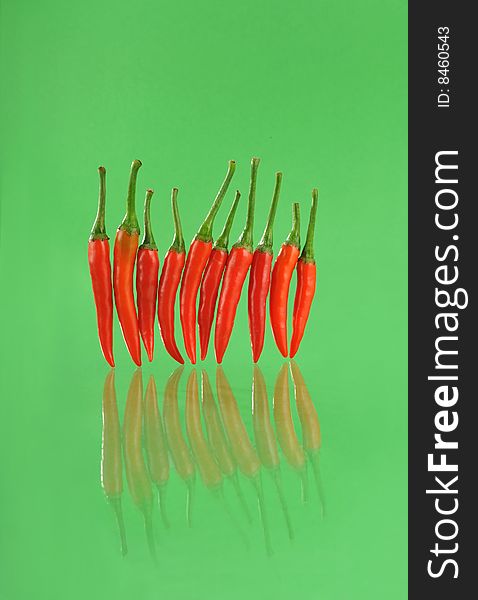 A row of red pepper on green background