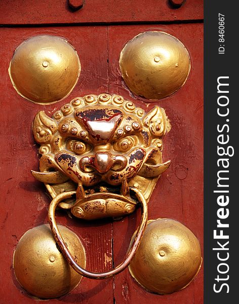 A gilded lion door knocker on a wooden red door at the Long Xing Pagoda in Pengzhou, Sichuan province, China - Lee Snider Photo. A gilded lion door knocker on a wooden red door at the Long Xing Pagoda in Pengzhou, Sichuan province, China - Lee Snider Photo.