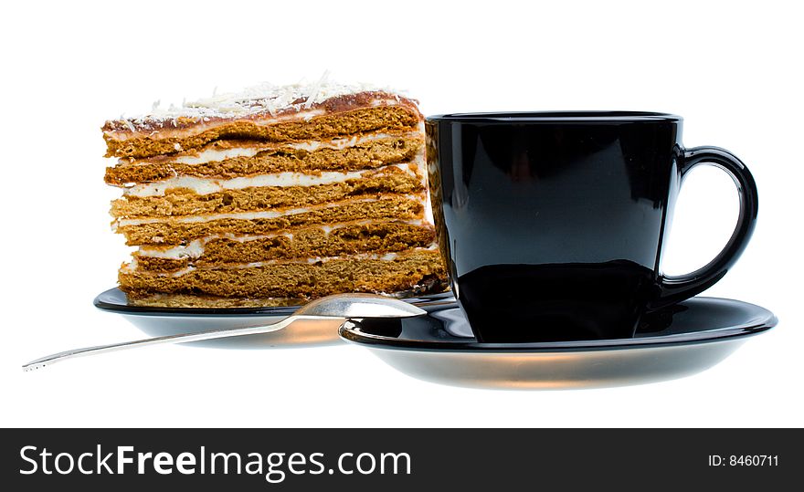 Black cup and piece of honey cake, isolated on white