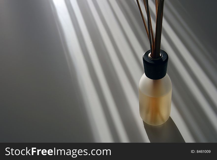 A bottle of natural scent dispenser caught from the light os sun beams on a white background. A bottle of natural scent dispenser caught from the light os sun beams on a white background