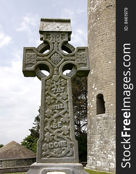 Old irish stone cross in front of a tower. Old irish stone cross in front of a tower