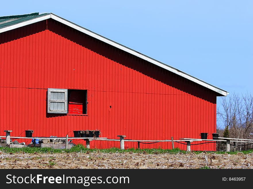 Broad side of a red barn with a window.
