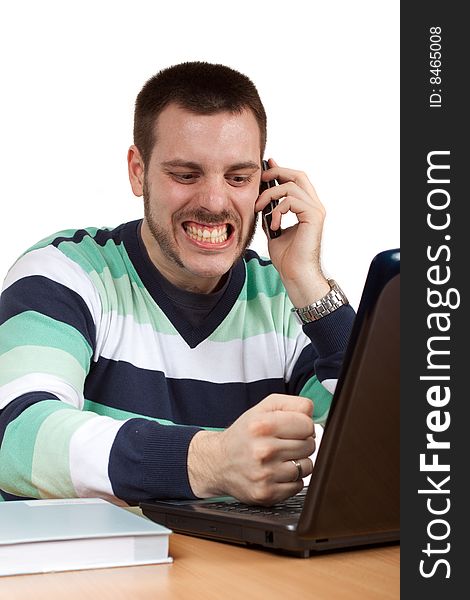 Angry young man talking on a mobile phone and trying to smash his notebook. Angry young man talking on a mobile phone and trying to smash his notebook