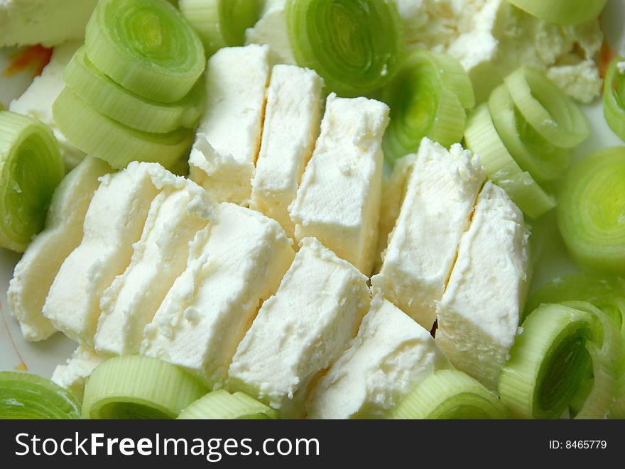 Cut green leek and white cheese slices closeup. Cut green leek and white cheese slices closeup