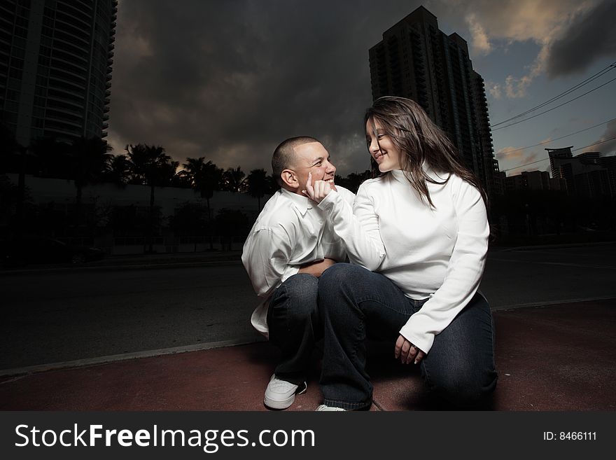 Happy young couple squatting in the street and showing affection towards eachother