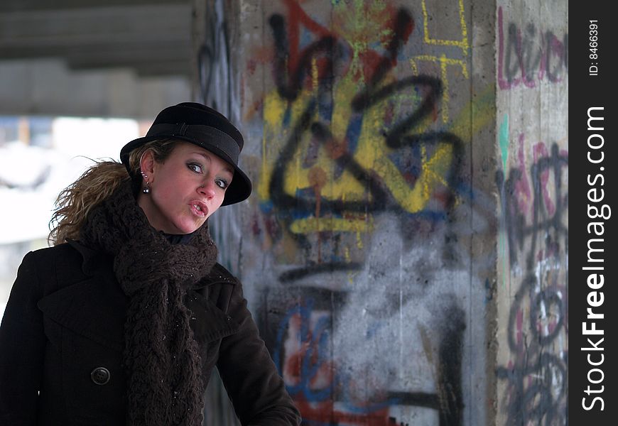 Curly girl with brown hat on graffiti wall background