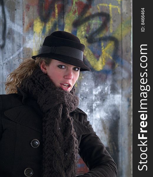 Curly girl with brown hat on graffiti wall background