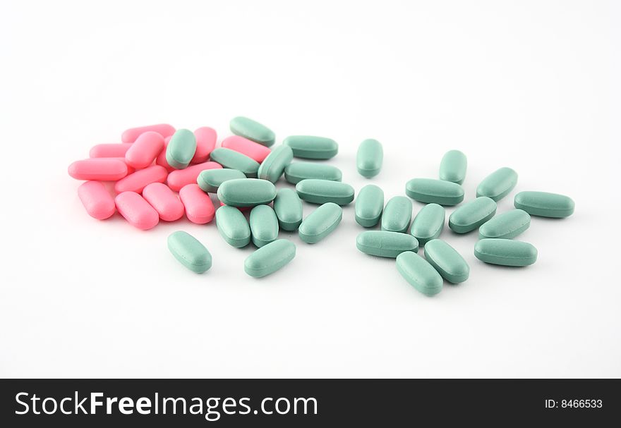 Pink and green pills displayed on white. Pink and green pills displayed on white