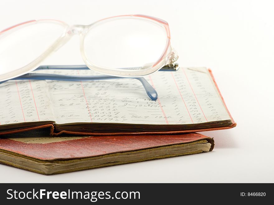 Two financial ledgers and a pair of glasses on a white background. Two financial ledgers and a pair of glasses on a white background
