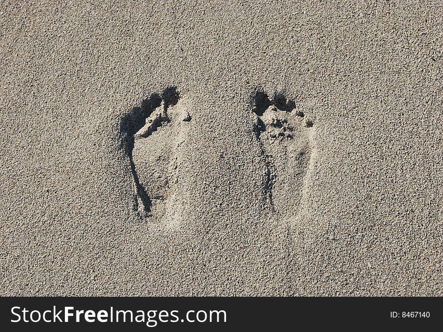 Two footprints in the soft sand on the beach showing outline of toes,  instep and heal. Two footprints in the soft sand on the beach showing outline of toes,  instep and heal.
