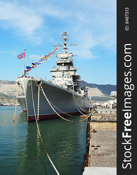 A battleship anchored in the harbour. The water is still