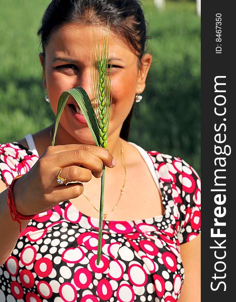 Girl holding a green wheat plant looking great.