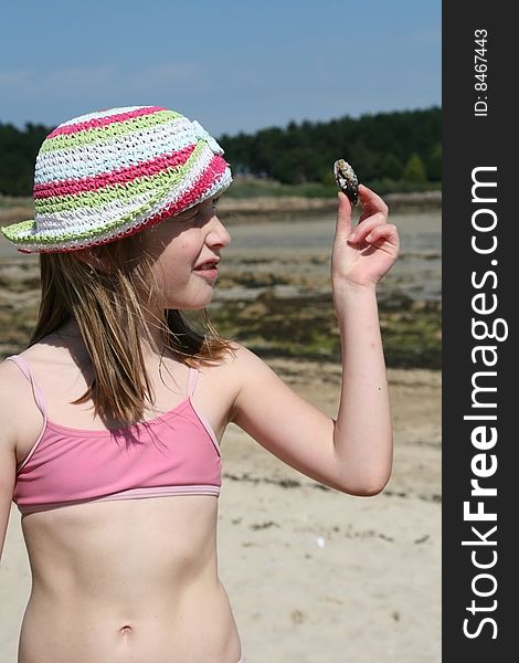 Teenage girl looking at a shell on the beach