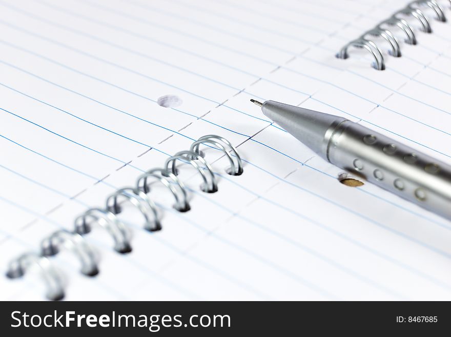 Metal mechanical pencil on a spiral-bound notepad. Metal mechanical pencil on a spiral-bound notepad