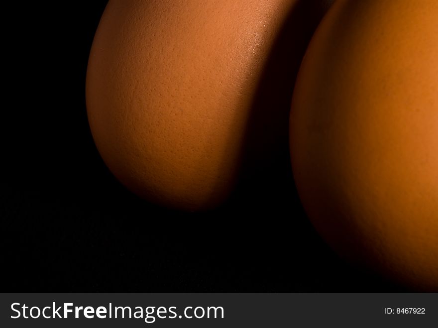 Two brown hen's eggs together in angled light with dark background. Two brown hen's eggs together in angled light with dark background