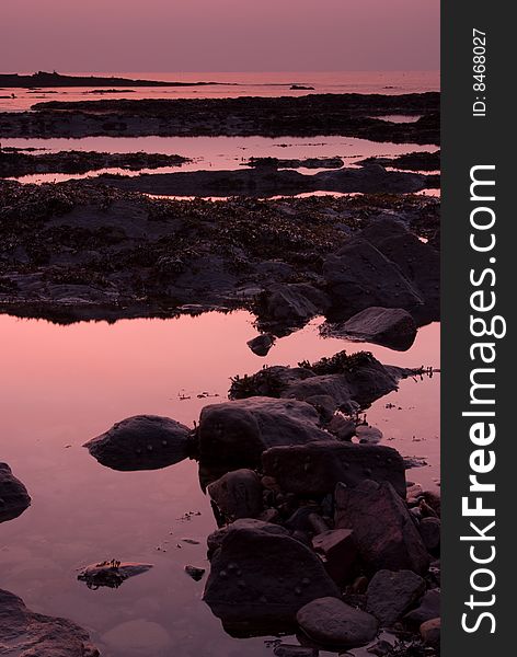 Pale purple sunrise reflected in pools of seawater in rocks in Scotland. Pale purple sunrise reflected in pools of seawater in rocks in Scotland