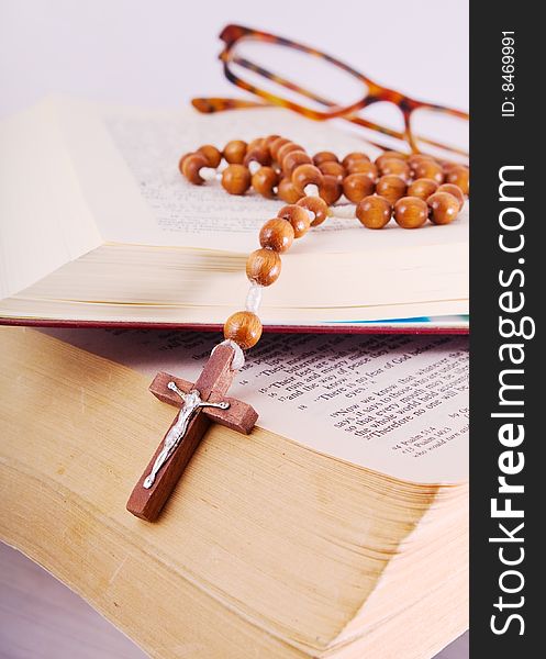 Open Holy Bible lying on stack of old books with glasses, cross and beads. Open Holy Bible lying on stack of old books with glasses, cross and beads