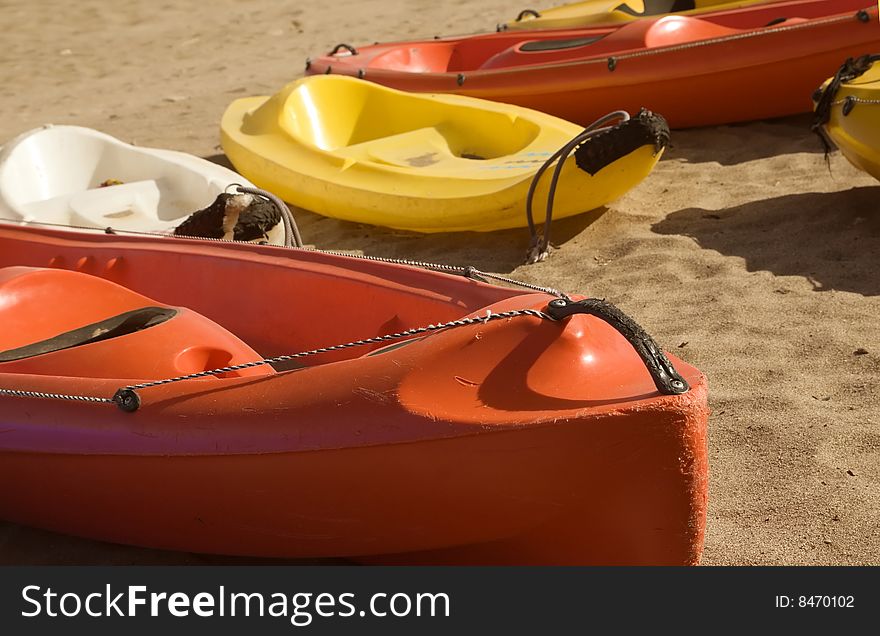 Close-up of a canoe nose on sandy beach, three more colourful canoes in background, in sunny weather. Close-up of a canoe nose on sandy beach, three more colourful canoes in background, in sunny weather