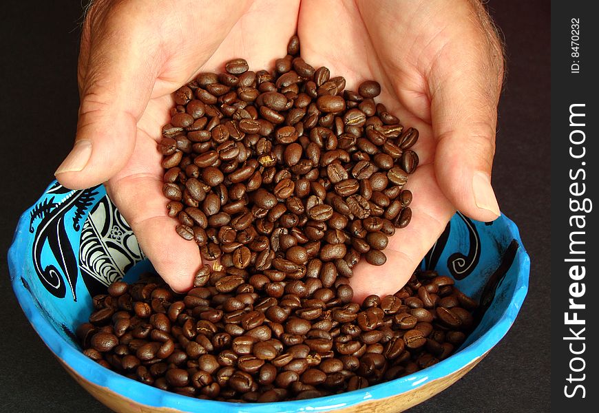 Male hands holding coffee beans with a blue bowl