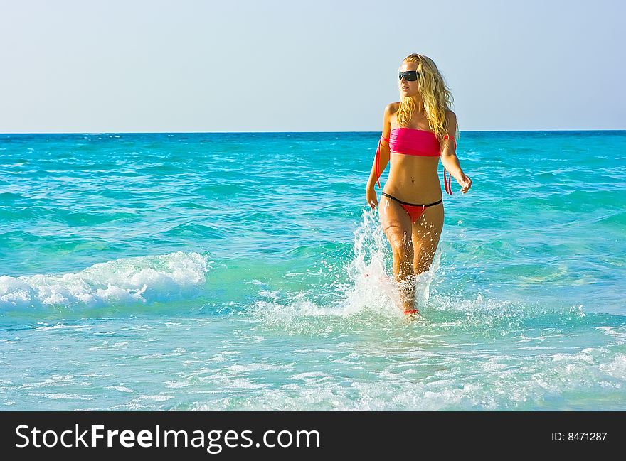 Blonde girl walking out of the surf. Blonde girl walking out of the surf